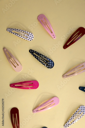 Colorful trendy hair clips on bright yellow background. Top view.