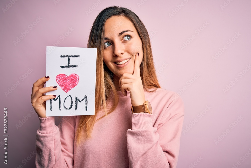Young beautiful woman holding paper with love mom message celebrating mothers day serious face thinking about question, very confused idea Young beautiful woman holding paper with love mom message celebrating mothers day serious face thinking about question, very confused idea