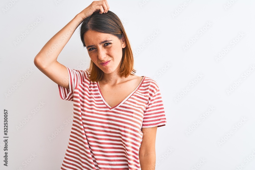 Beautiful redhead woman wearing casual striped red t-shirt over isolated background confuse and wonder about question. Uncertain with doubt, thinking with hand on head. Pensive concept. Beautiful redhead woman wearing casual striped red t-shirt over isolated background confuse and wonder about question. Uncertain with doubt, thinking with hand on head. Pensive concept.
