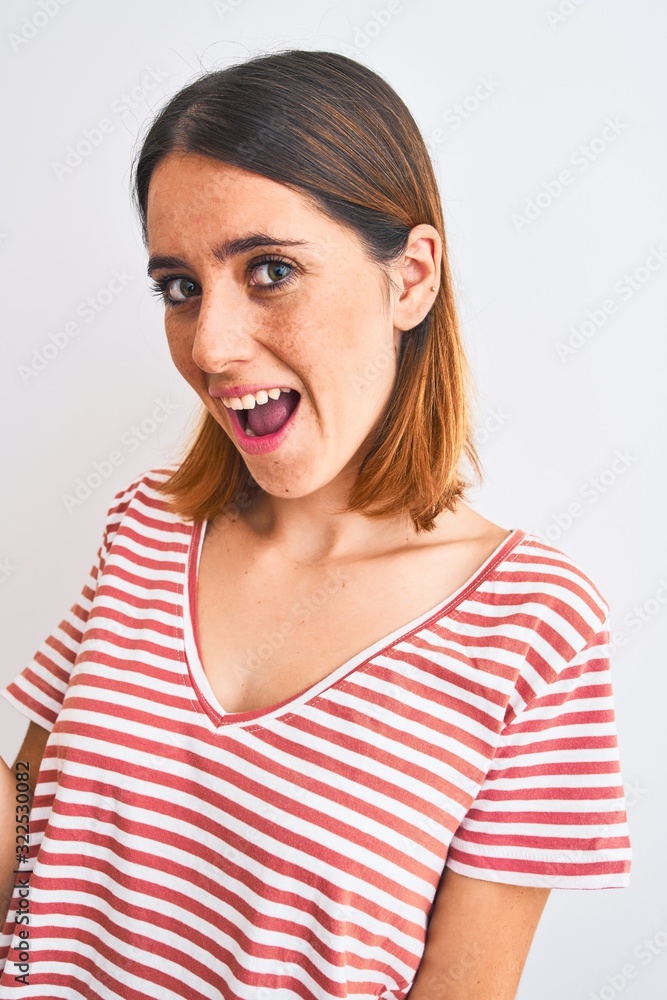 Beautiful redhead woman wearing casual striped red t-shirt over isolated background pointing and showing with thumb up to the side with happy face smiling Beautiful redhead woman wearing casual striped red t-shirt over isolated background pointing and showing with thumb up to the side with happy face smiling