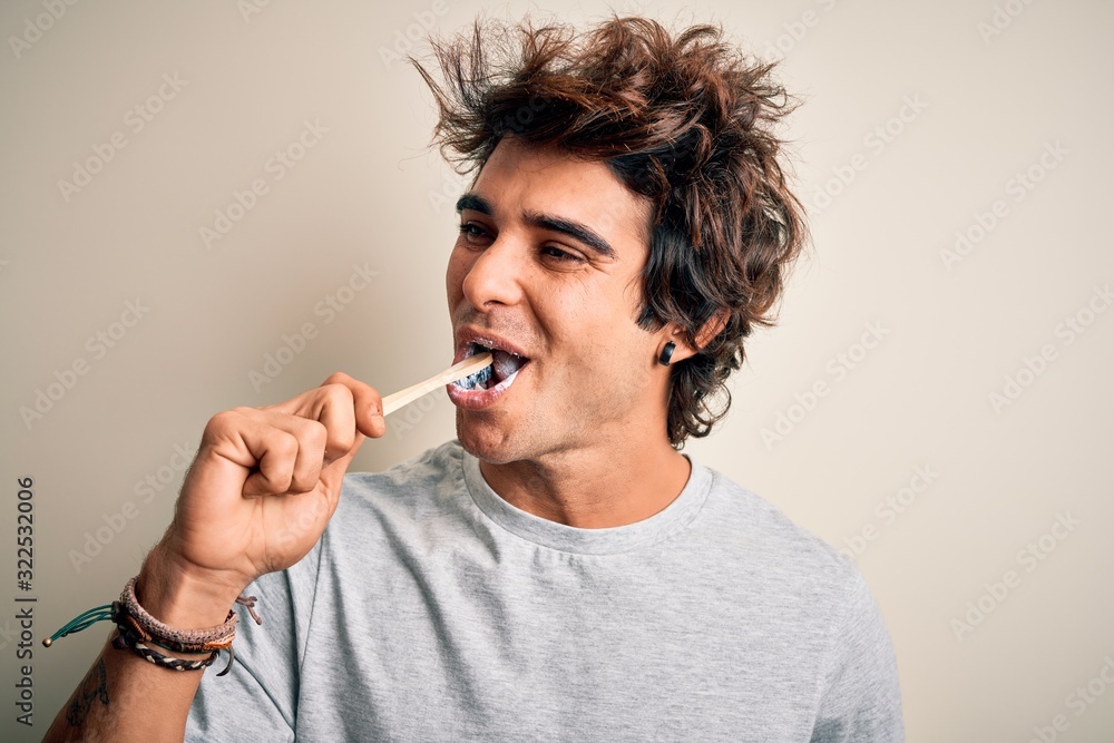 Young handsome man smiling happy. Standing with smile on face whasing tooth using toothbrush over isolated white background Young handsome man smiling happy. Standing with smile on face whasing tooth using toothbrush over isolated white background