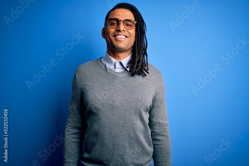 Young handsome african american man with dreadlocks wearing casual sweater and glasses with a happy and cool smile on face. Lucky person.