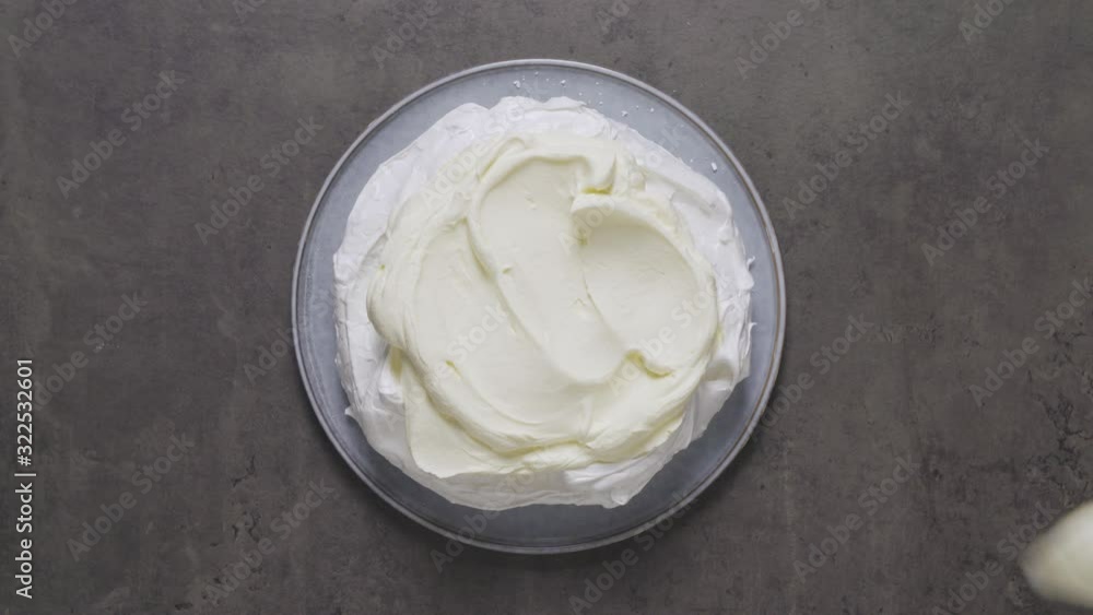 Pavlova being made with spreading of whipped cream Pavlova being made with spreading of whipped cream