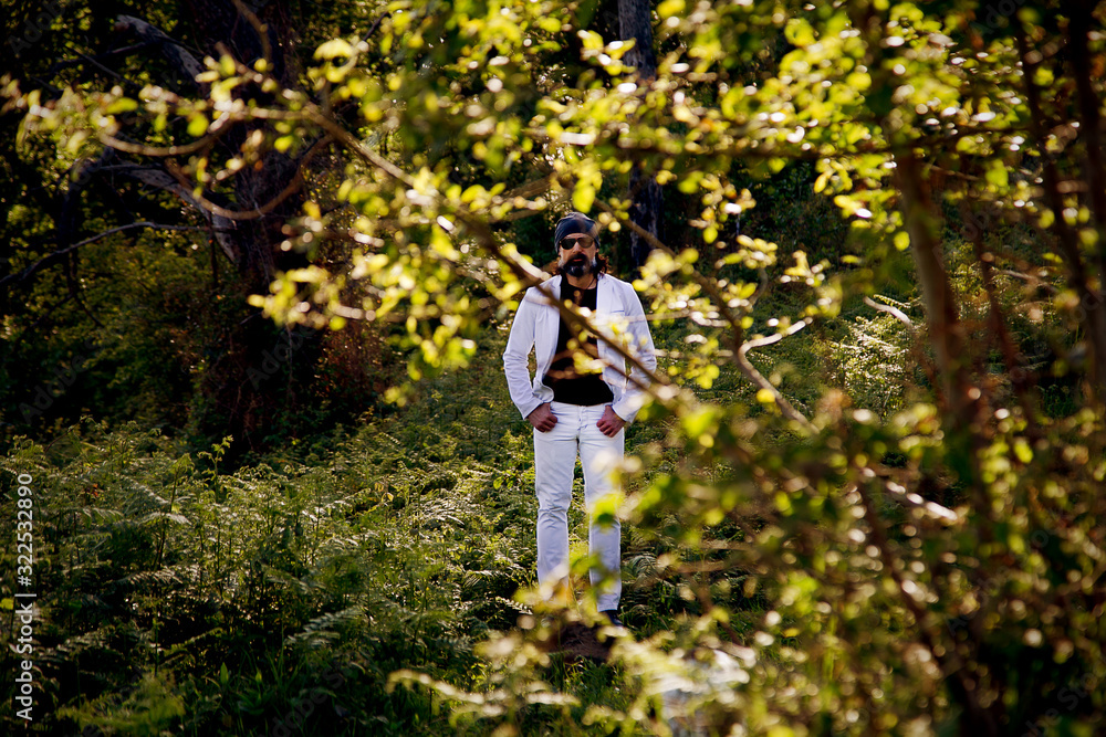 a serious man with a beard, in a gray hat, in white jeans, walking in nature a serious man with a beard, in a gray hat, in white jeans, walking in nature