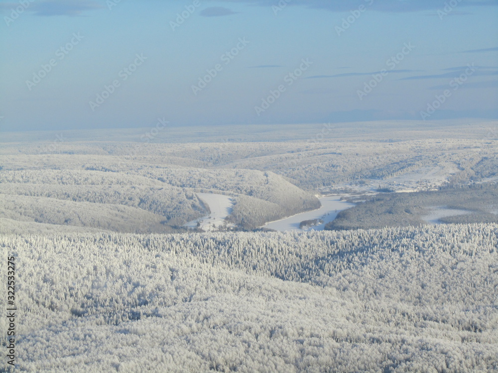 Winter landscape with mountains, river and blue sky. View from the top of the mountain.