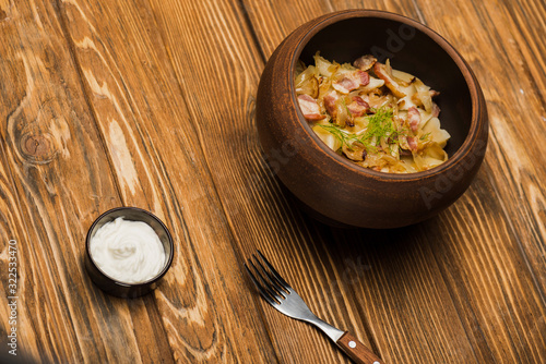 delicious varenyky with cracklings in bowl served with sour cream on wooden table