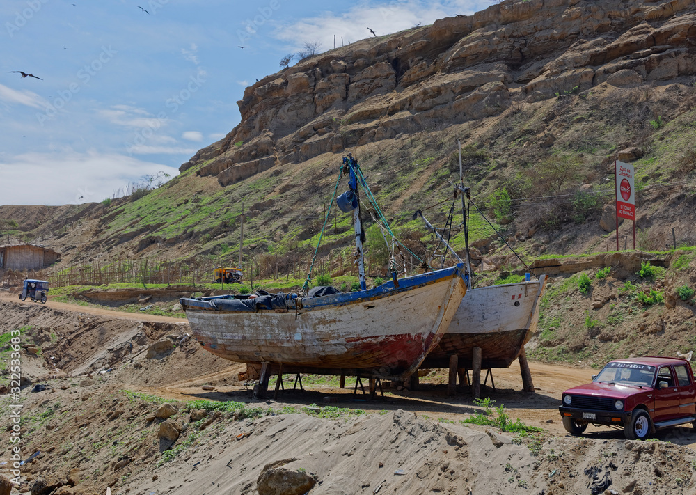 Two wooden Peruvian Fishing Boats propped up on land waiting for some maintenance beneath the sandstone cliffs of Mancora. Two wooden Peruvian Fishing Boats propped up on land waiting for some maintenance beneath the sandstone cliffs of Mancora.