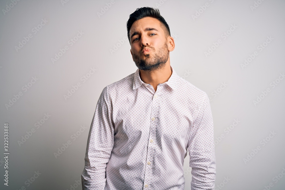 Young handsome man wearing elegant shirt standing over isolated white background looking at the camera blowing a kiss on air being lovely and sexy. Love expression. Young handsome man wearing elegant shirt standing over isolated white background looking at the camera blowing a kiss on air being lovely and sexy. Love expression.