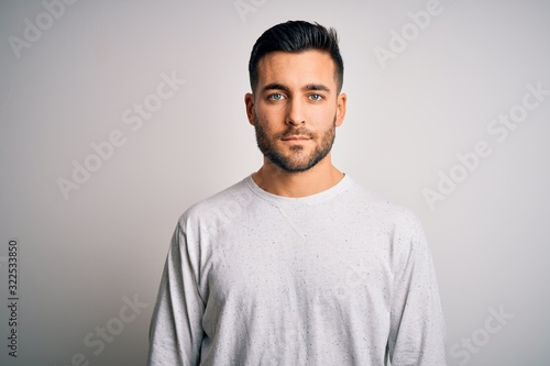Young handsome man wearing casual t-shirt standing over isolated white background with serious expression on face. Simple and natural looking at the camera. photo