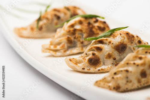 close up view of delicious gyoza served on plate on white background