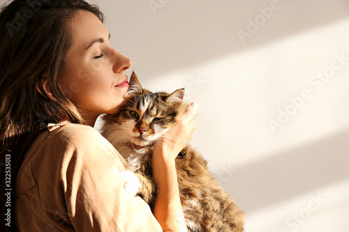 Fototapeta Portrait of young woman holding cute siberian cat with green eyes