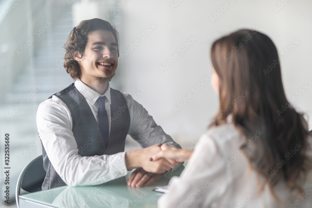 Friendly smiling businessman and businesswoman handshaking over the office desk after pleasant talk and effective negotiation, good relationships. Business concept photo Friendly smiling businessman and businesswoman handshaking over the office desk after pleasant talk and effective negotiation, good relationships. Business concept photo
