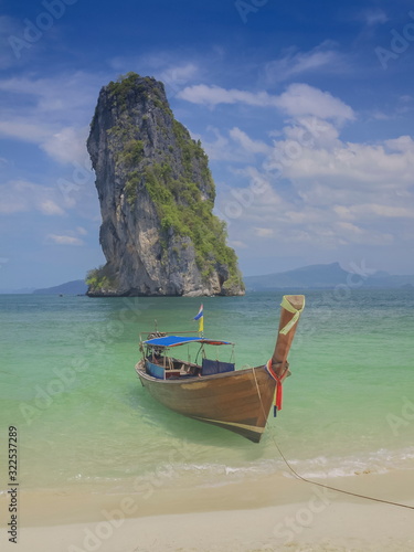 view seaside of a long-tail boat floating in blue-green sea with cliff mountain and cloudy sky background, Ko Poda island, Krabi, southern of Thailand. © Yuttana Joe