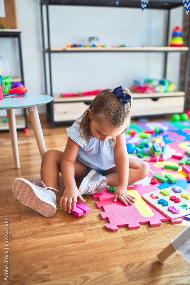 Young beautiful blonde girl kid enjoying play school with toys at kindergarten, smiling happy playing at home