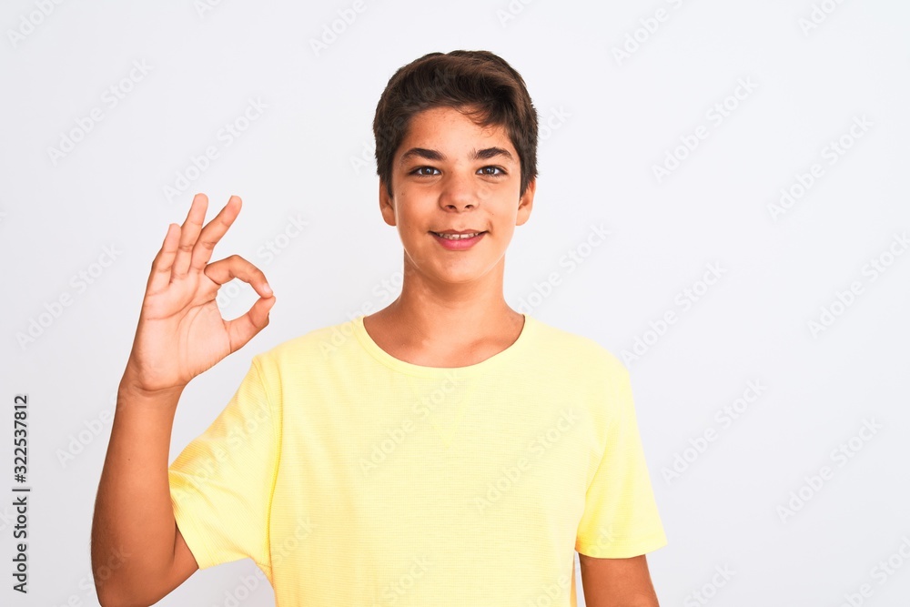 Handsome teenager boy standing over white isolated background smiling positive doing ok sign with hand and fingers. Successful expression. Handsome teenager boy standing over white isolated background smiling positive doing ok sign with hand and fingers. Successful expression.