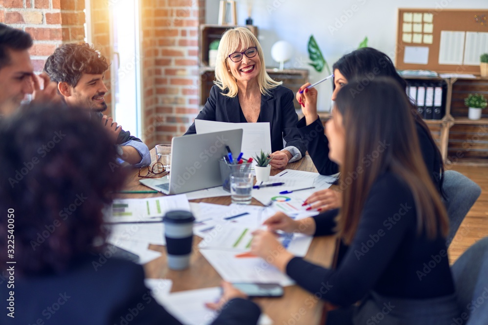 Group of business workers smiling happy and confident. Working together with smile on face using laptop and speaking at the office Group of business workers smiling happy and confident. Working together with smile on face using laptop and speaking at the office