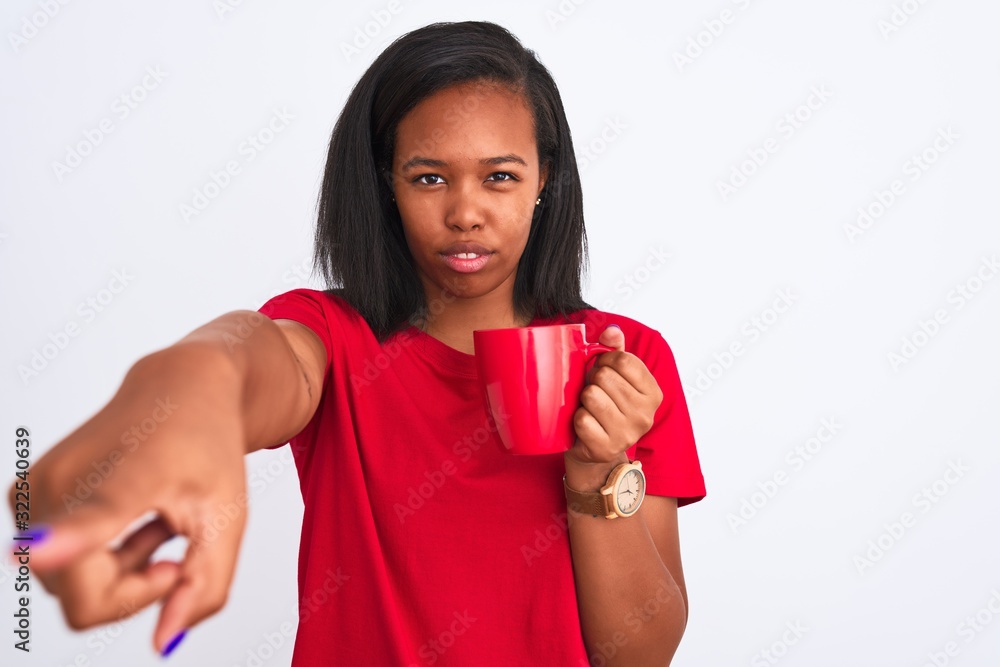 Young african american woman drinking a cup of coffee over isolated background pointing with finger to the camera and to you, hand sign, positive and confident gesture from the front Young african american woman drinking a cup of coffee over isolated background pointing with finger to the camera and to you, hand sign, positive and confident gesture from the front