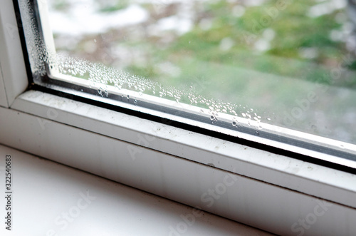 Drops of condensate and black mold on a white plastic window.