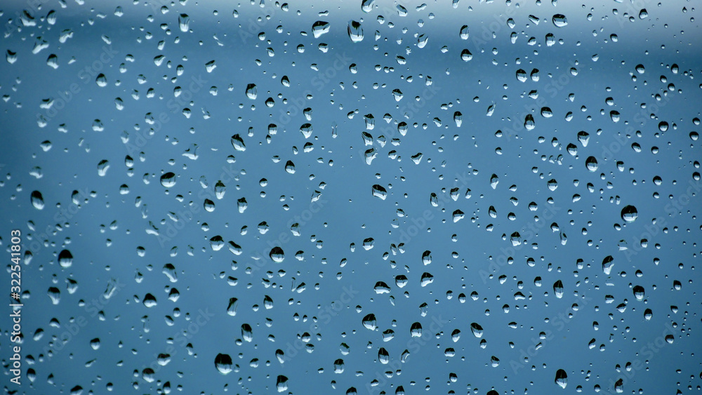 Crystal clear water drops on the window with blue background; raindrops on the window Crystal clear water drops on the window with blue background; raindrops on the window
