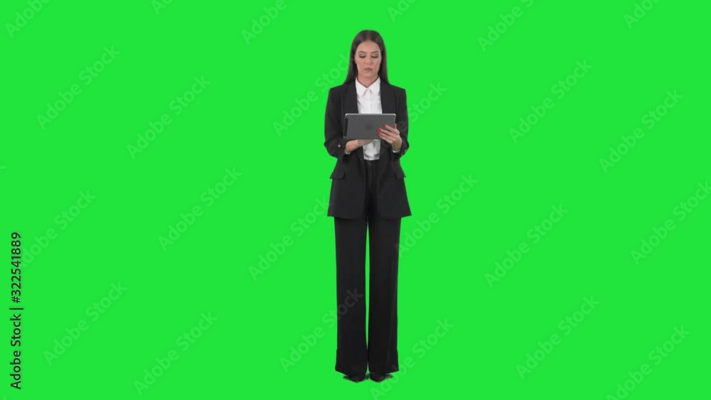 Serious busy young business woman using tablet computer interacting with touch screen. Full length on green screen background. Serious busy young business woman using tablet computer interacting with touch screen. Full length on green screen background.