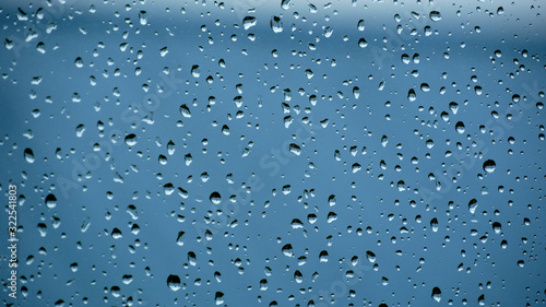 Crystal clear water drops on the window with blue background; raindrops on the window