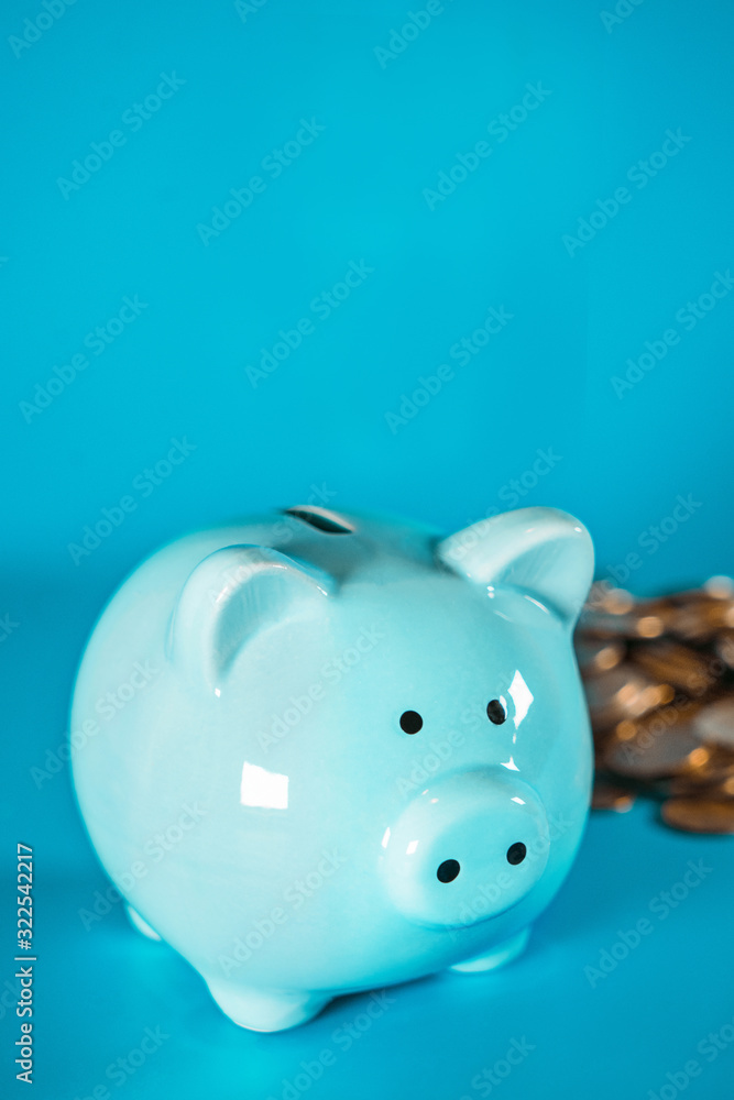 Image of a blue piggy bank standing on a white desk surface with copy space on the background. Image of a blue piggy bank standing on a white desk surface with copy space on the background.
