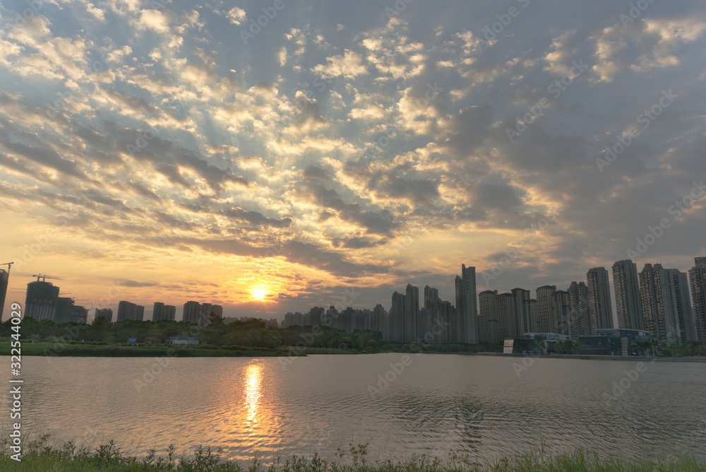 Sunset scenery of a city park; sunset reflects on a lake surface in cloudy weather