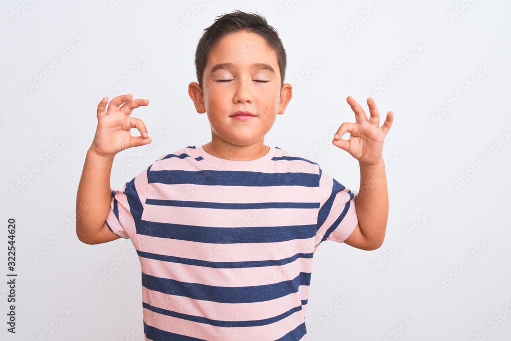 Beautiful kid boy wearing casual striped t-shirt standing over isolated white background relax and smiling with eyes closed doing meditation gesture with fingers. Yoga concept. Beautiful kid boy wearing casual striped t-shirt standing over isolated white background relax and smiling with eyes closed doing meditation gesture with fingers. Yoga concept.