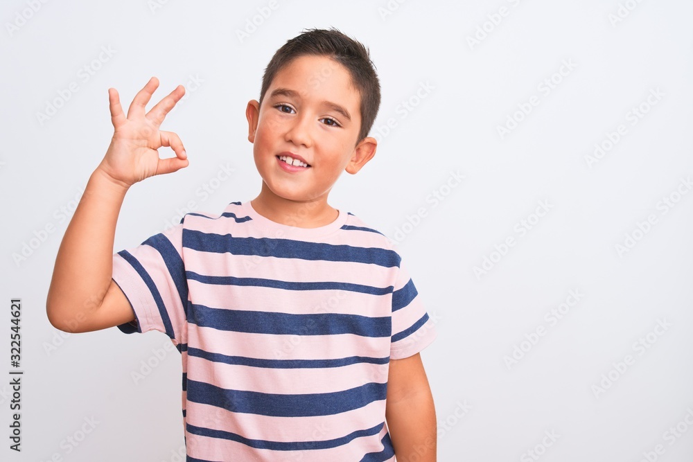 Beautiful kid boy wearing casual striped t-shirt standing over isolated white background smiling positive doing ok sign with hand and fingers. Successful expression. Beautiful kid boy wearing casual striped t-shirt standing over isolated white background smiling positive doing ok sign with hand and fingers. Successful expression.