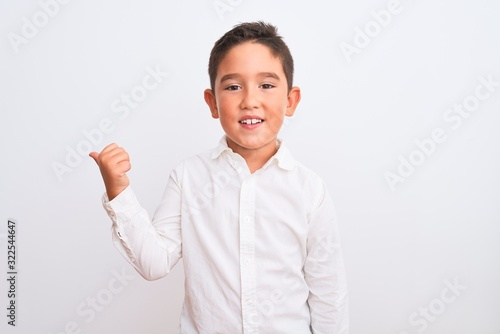 Beautiful kid boy wearing elegant shirt standing over isolated white background smiling with happy face looking and pointing to the side with thumb up.