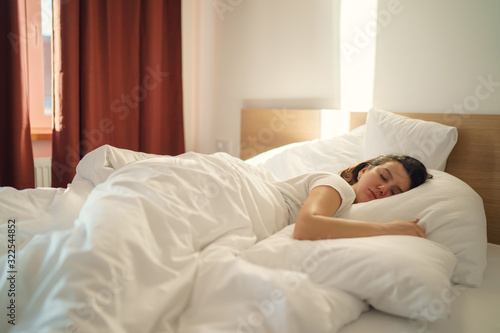 Young beautiful alone woman sleeping on bed in bedroom
