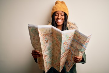 Young african american girl going on vacation holding turist city map over isolated background with a happy face standing and smiling with a confident smile showing teeth