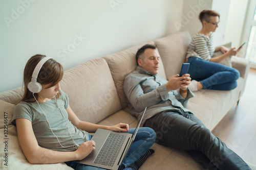 Fotografía Technology addicted family: parents and child use laptop and mobile phones