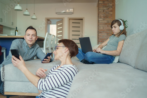 Slika na platnu Technology addicted family: parents and child use laptop and mobile phones