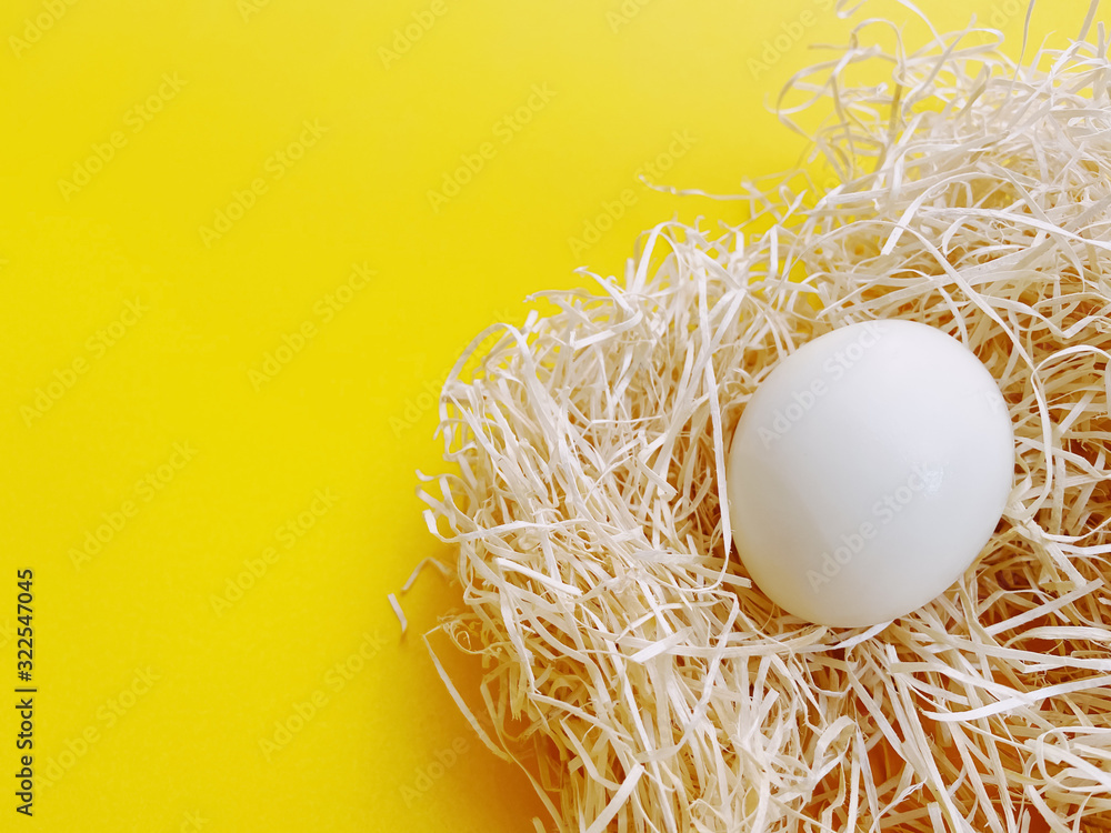 A white chicken eggs are placed in the hay lay flat on yellow background, close up in the bottom right of the frame with copy space. A white chicken eggs are placed in the hay lay flat on yellow background, close up in the bottom right of the frame with copy space.
