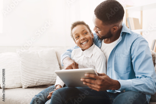 Afro father and daughter ordering clothes and toys on tablet