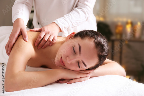 Portrait young beautiful woman lying on the massage table in spa wellness salon. Beauty and health procedures for women concept. Close up, copy space, background.