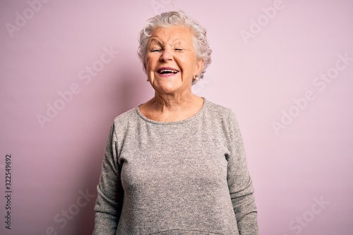 Senior beautiful woman wearing casual t-shirt standing over isolated pink background winking looking at the camera with sexy expression, cheerful and happy face. photo