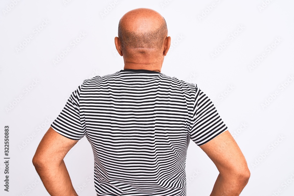 Middle age handsome man wearing striped navy t-shirt over isolated white background standing backwards looking away with arms on body Middle age handsome man wearing striped navy t-shirt over isolated white background standing backwards looking away with arms on body