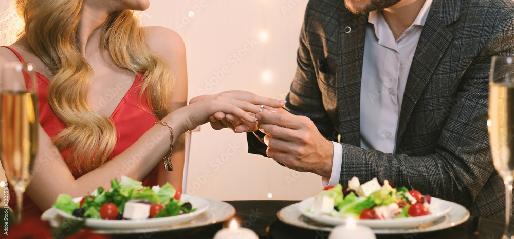 Unrecognizable Man Putting Ring On Girlfriend's Hand During Dinner In Restaurant Unrecognizable Man Putting Ring On Girlfriend's Hand During Dinner In Restaurant