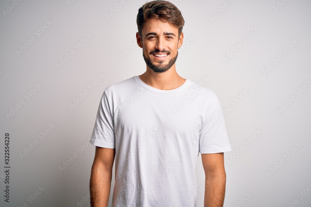 Young handsome man with beard wearing casual t-shirt standing over white background with a happy and cool smile on face. Lucky person. Young handsome man with beard wearing casual t-shirt standing over white background with a happy and cool smile on face. Lucky person.