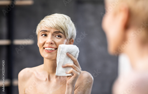 Lady Drying Face With Towel Doing Skincare Routine In Bathroom