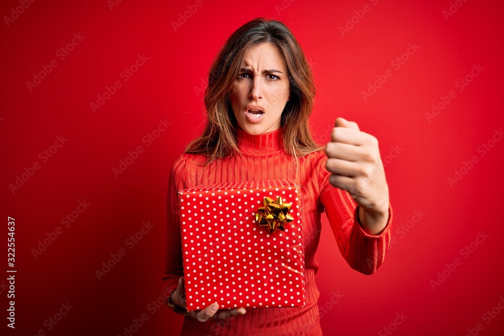 Young beautiful brunette woman holding birthday gift over isolated red background annoyed and frustrated shouting with anger, crazy and yelling with raised hand, anger concept Young beautiful brunette woman holding birthday gift over isolated red background annoyed and frustrated shouting with anger, crazy and yelling with raised hand, anger concept