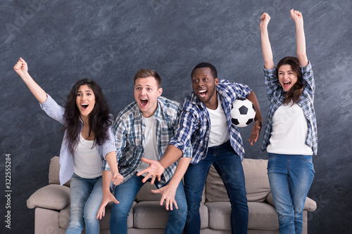 Excited multiethnic friends watching football at home