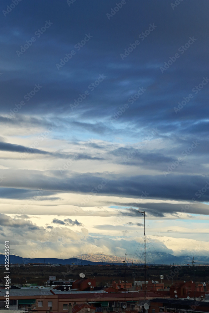  A view of the mountains, with a cloudy sky and an antenna and rooftops