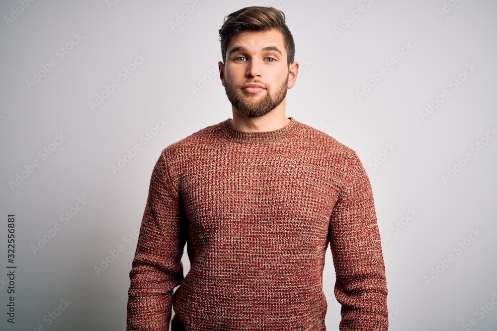 Young blond man with beard and blue eyes wearing casual sweater over white background Relaxed with serious expression on face. Simple and natural looking at the camera. Young blond man with beard and blue eyes wearing casual sweater over white background Relaxed with serious expression on face. Simple and natural looking at the camera.