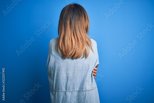 Middle age beautiful woman wearing casual shirt standing over isolated blue background Hugging oneself happy and positive from backwards. Self love and self care