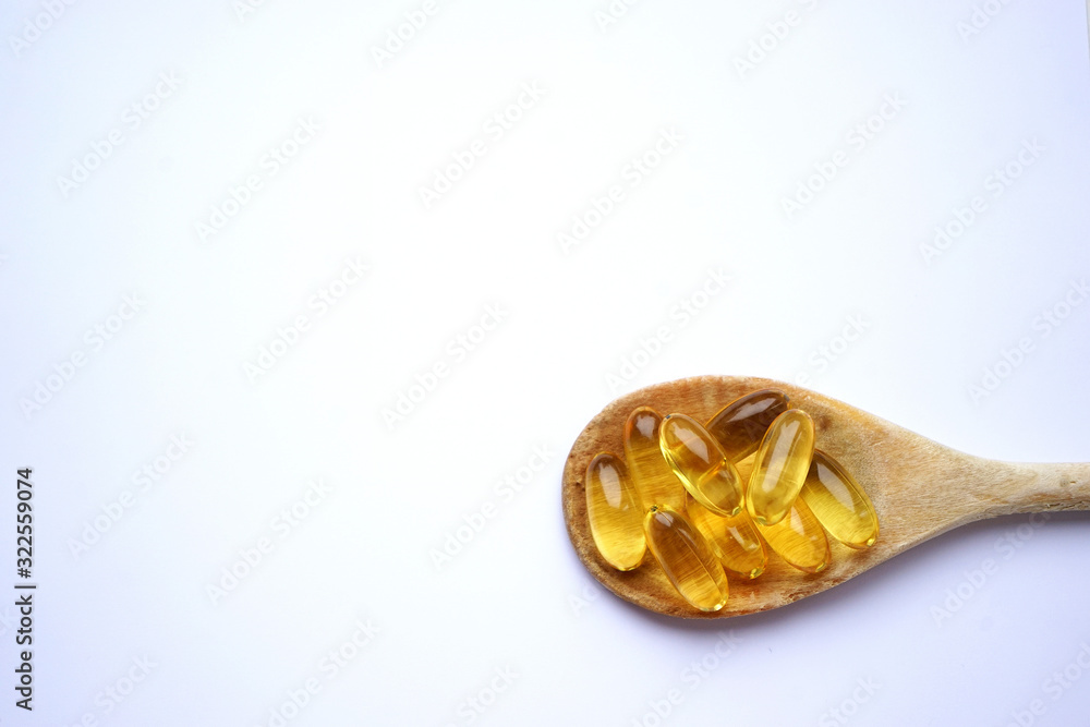 Fish oil Omega 3 vitamins and supplements on a wooden spoon Fish oil Omega 3 vitamins and supplements on a wooden spoon