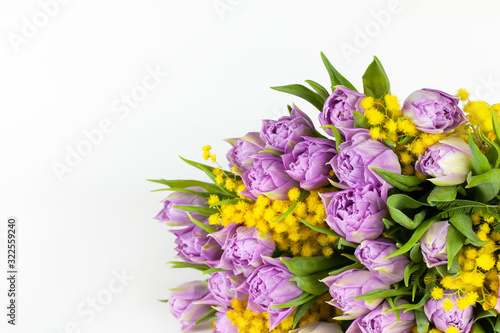 Bouquet of lilac tulips and yellow mimosas on white background, copy space, side view, closeup. March 8, February 14, birthday, Valentine's, Mother's, Women's day celebration, spring concept