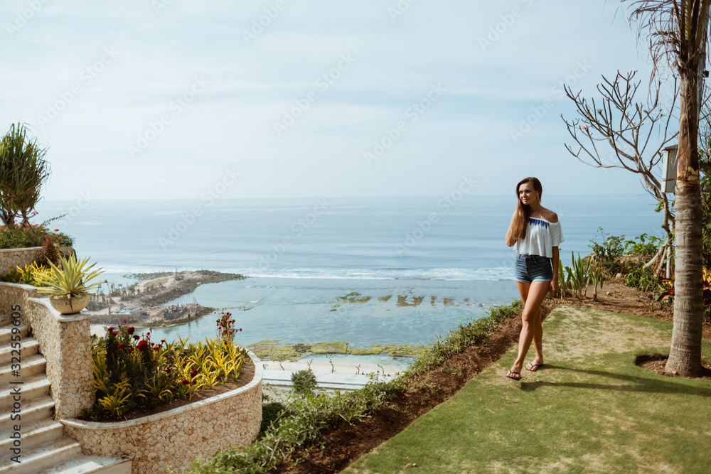 Outdoor summer portrait of young pretty woman looking to the ocean at tropical beach